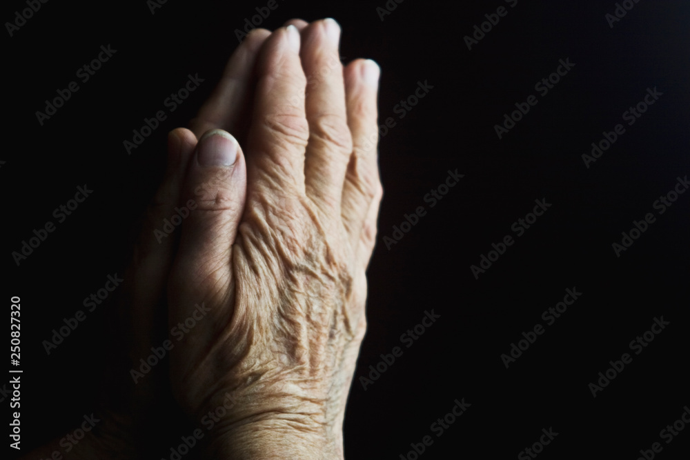 Grandma's old wrinkled hands praying for their loved ones Grandma's old wrinkled hands praying for their loved ones