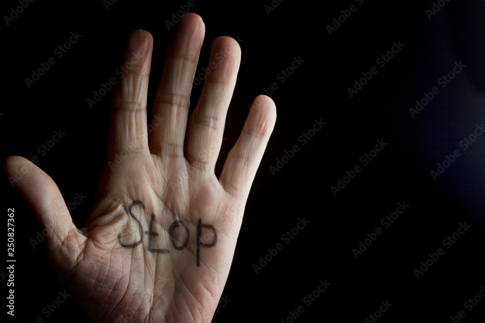 Fototapeta premium The palm of an old grandmother with the word stop on a dark background
