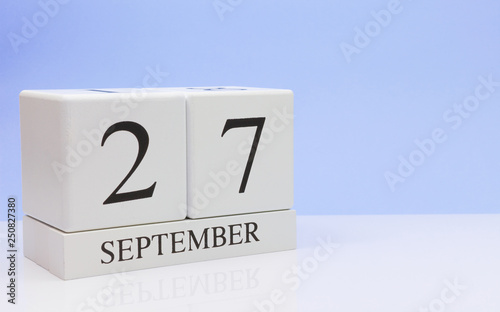 September 27st. Day 27 of month, daily calendar on white table with reflection, with light blue background. Autumn time, empty space for text