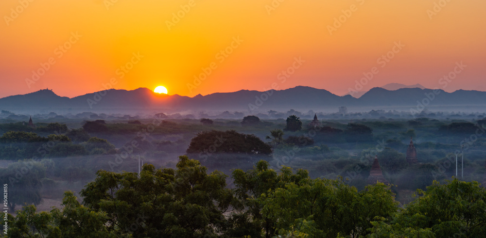 sun rising over mountains  in Bagan on a misty foggy morning at dawn