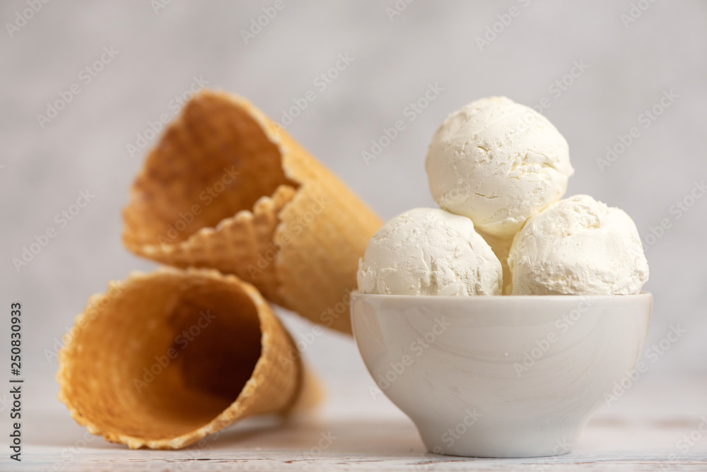 Bowl of vanilla ice cream and waffle cones on light background. Side view Bowl of vanilla ice cream and waffle cones on light background. Side view