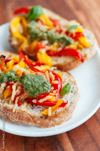 Red and yellow bell pepper, vegan cheese and home made vegan basil pesto on toasted slices of bread.