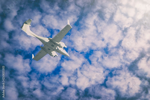 a small private white plane with screws flies on the background blue sky with clouds