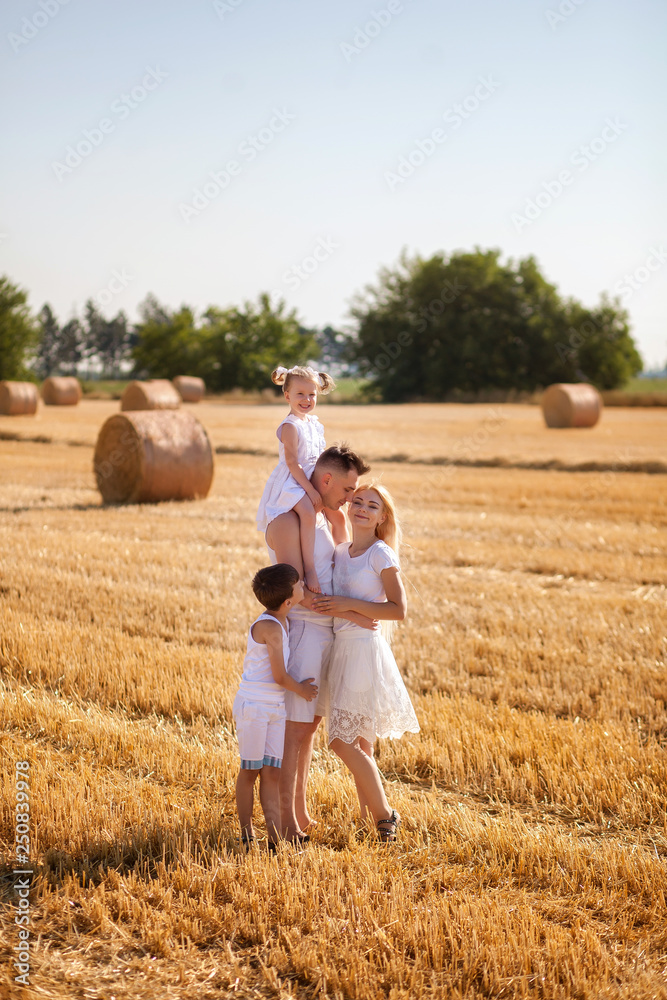 happy family, mom, dad, son and daughter in the field against the haystack, in the morning, in white clothes