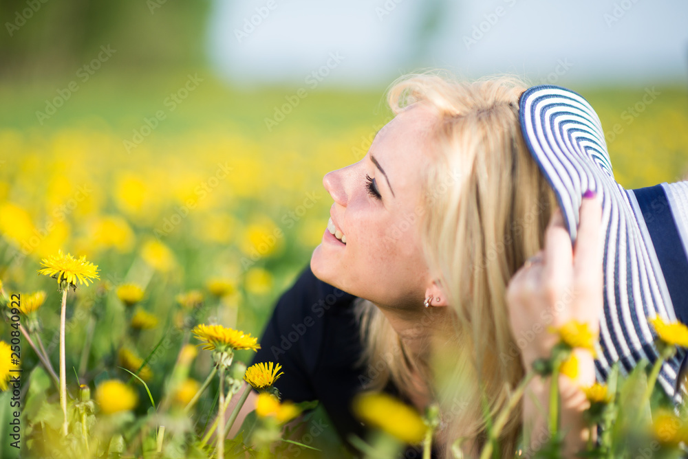 Image of pretty woman lying down on dandelions field, happy cheerful girl resting on dandelions meadow, relaxation outdoor in springtime, vacation Image of pretty woman lying down on dandelions field, happy cheerful girl resting on dandelions meadow, relaxation outdoor in springtime, vacation