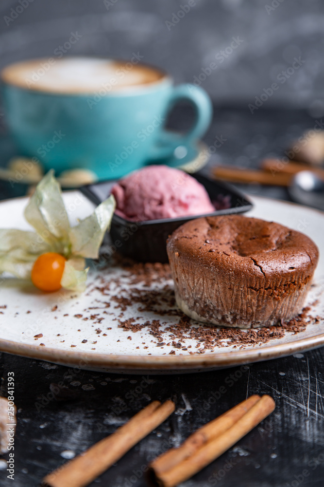 Chocolate lava cake Molten with ice cream on plate and cappuccino. Balls of ice cream in cup . Dark black background.