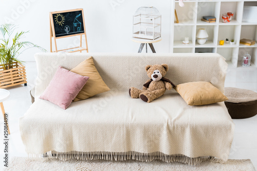 cosy living room with pillows and teddy bear assembled on comfortable sofa
