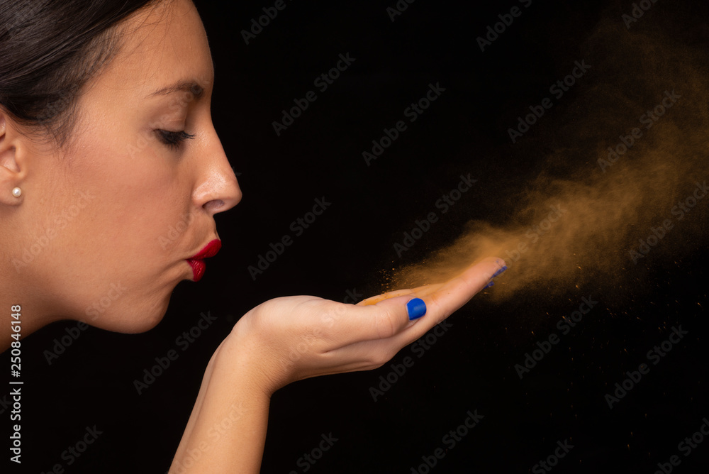 Fototapeta premium ragazza soffia brillantini azzurri su fondo nero