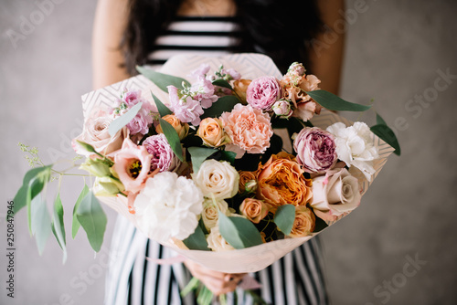 Wallpaper Mural Very nice young woman holding beautiful blossoming bouquet of fresh peonies, roses, eustoma, carnations, eucalyptus flowers in pink and pastel cream colors on the grey wall background  Torontodigital.ca