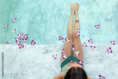 Girl relaxing in tropical spa pool with flowers