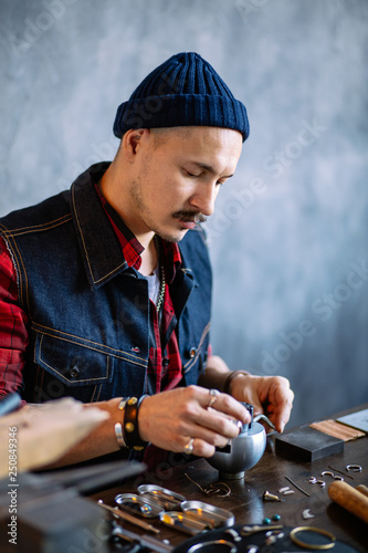 young talented craftsman using engraving block. jewelry accessory, close up side view photo