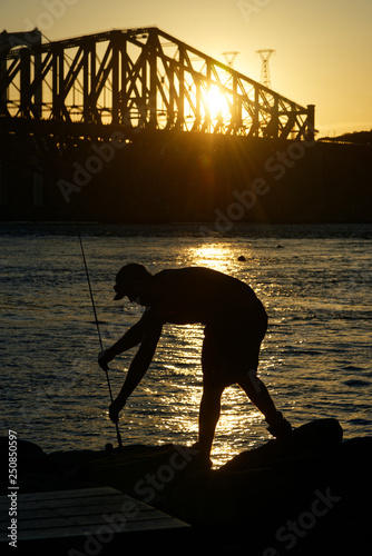A fisherman setting up his rod,  Parc de la Marina-de-la-Chaudière, St-Romuald, Quebec, with the St Lawrence Rier in Pont du Quebec behind photo