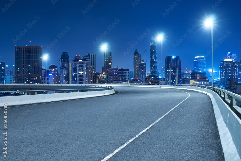 High speed corner overpass asphalt road with Bangkok cityscape , night scene .