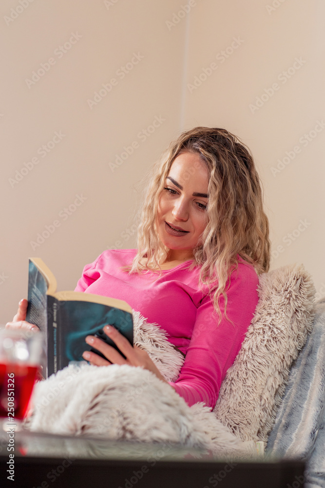 Young woman resting in bed with book. Young woman resting in bed with book.