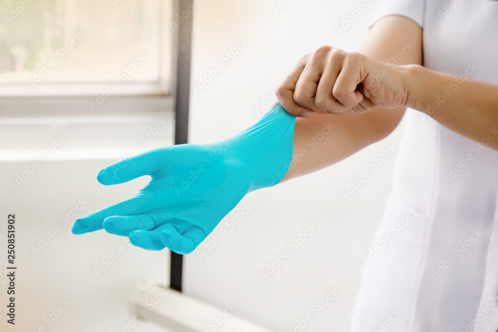 The doctor hand wearing blue sterilixed surgical gloves in hand,for protection,health care and medical concept The doctor hand wearing blue sterilixed surgical gloves in hand,for protection,health care and medical concept