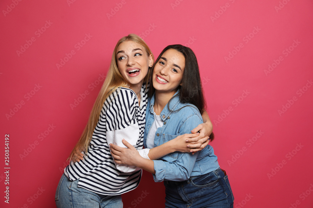 Young women laughing together against color background Young women laughing together against color background