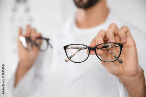 Male ophthalmologist with eyeglasses in clinic, closeup. Space for text