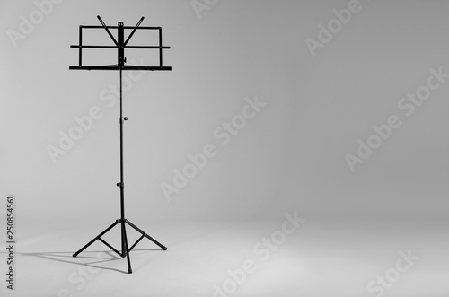 Empty music note stand on grey background. Space for text photo