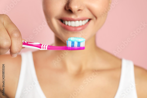 Young woman with toothbrush and paste on color background, closeup. Teeth care