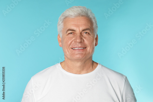 Mature man with healthy teeth on color background
