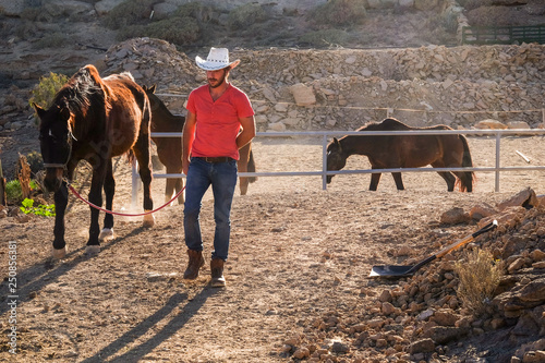 Red shirt cowboy farmer man working with horses in outdoor country side place - nice alternative free lifestyle for people enjoying the nature and the animals photo