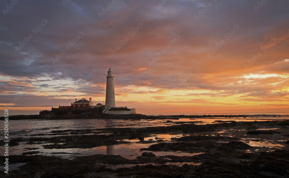 A sunrise with at St Mary's Lighthouse, Whitley Bay as beautiful colours are reflected on the clouds