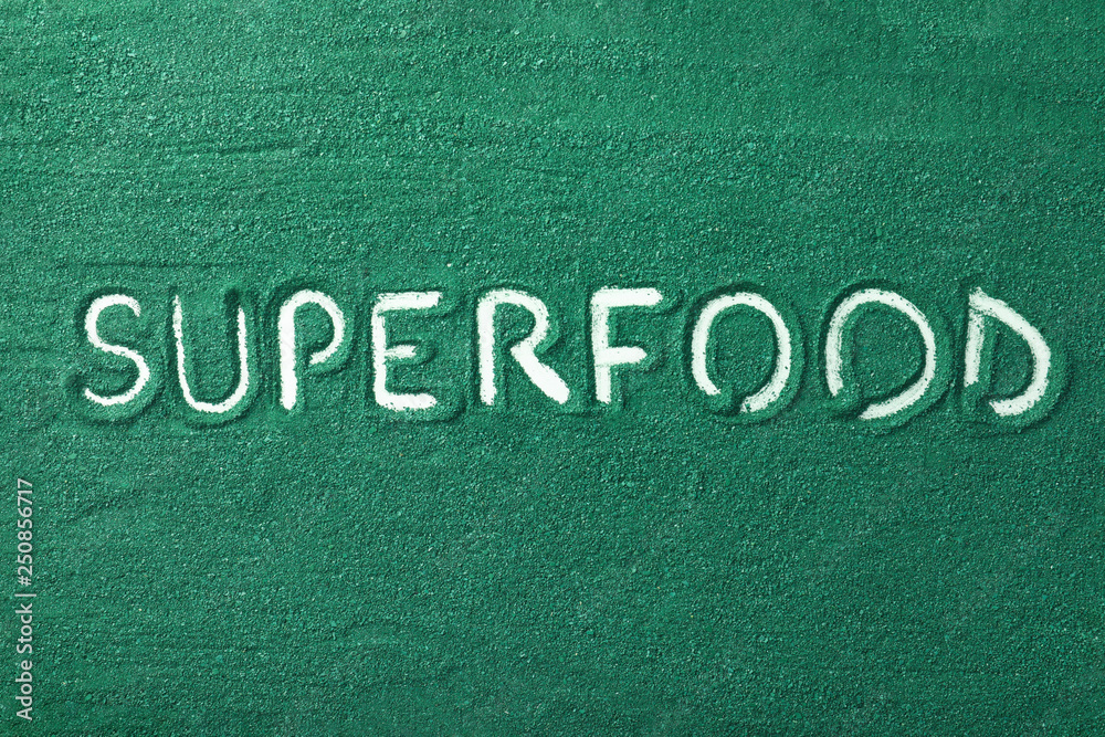 Word SUPERFOOD written in spirulina algae powder as background, top view Word SUPERFOOD written in spirulina algae powder as background, top view