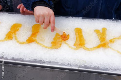 Photos Close up of a young (5 yr old) child's hand rolling maple syrup taffy onto a sti