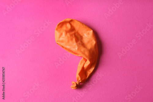 Orange deflated balloon on color background, top view photo