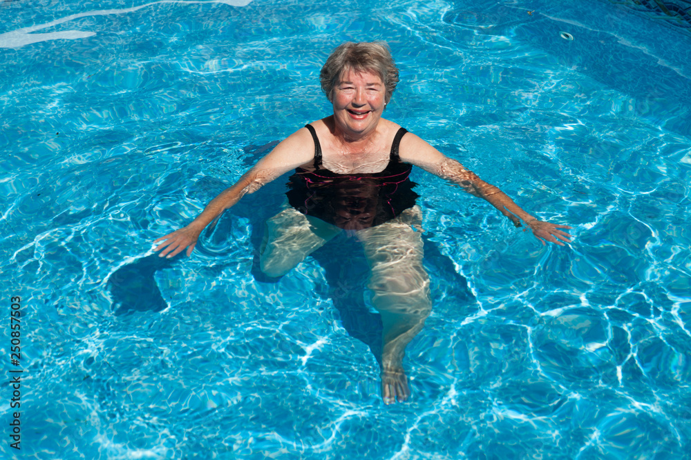 Old Woman doing exercises in a pool. She is smiling 