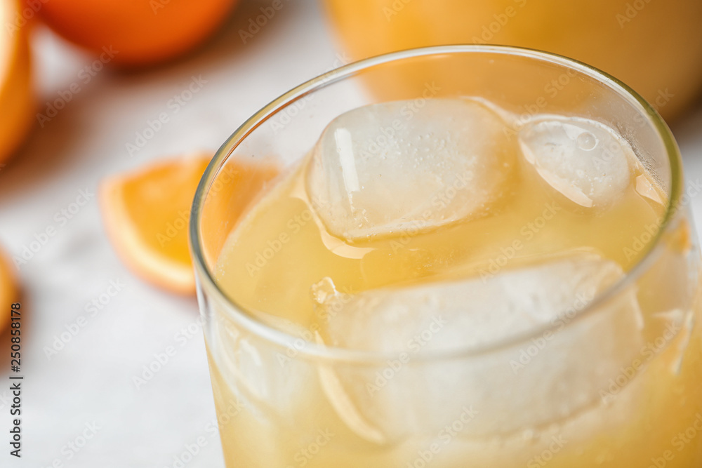 Glass of orange juice with ice cubes on table, closeup Glass of orange juice with ice cubes on table, closeup