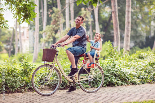 Happy Dad and son riding bicycles outdoors.