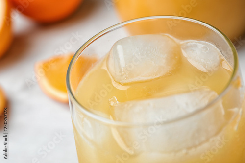 Glass of orange juice with ice cubes on table, closeup