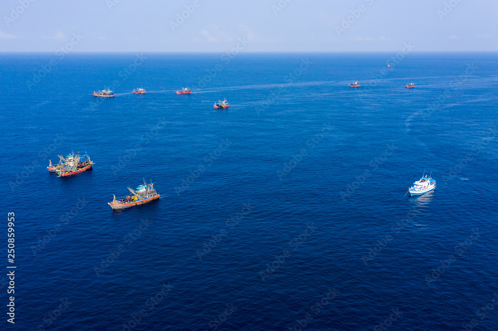 Overfishing - aerial view of a SCUBA diving boat surrounded by large industrial fishing trawlers around a conservation site in Myanmar