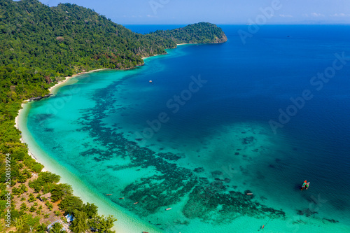 Aerial drone view of a beautiful tropical island surrounded by coral reefs and covered with lush, green jungle (Kyun Phi Lar, Myanmar)