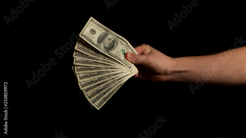 Fan of dollars in a male hand on a black background