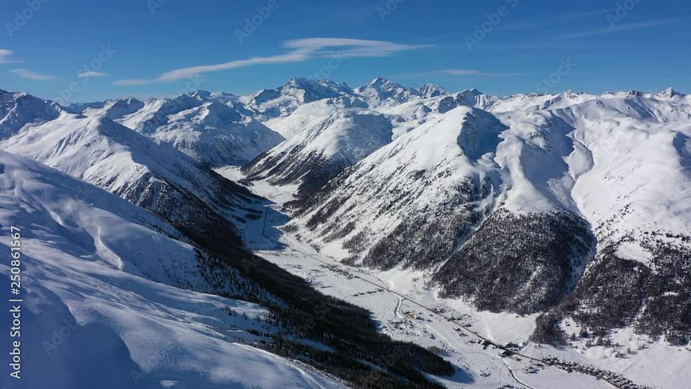 Aerial panoramic view of Alps, landscape panorama of snowy mountain range in winter, sunny day with blue sky - Alps from above, Livigno, Italy, Europe Aerial panoramic view of Alps, landscape panorama of snowy mountain range in winter, sunny day with blue sky - Alps from above, Livigno, Italy, Europe