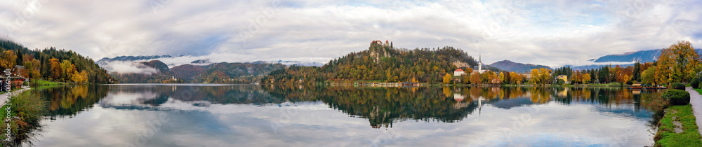Beautiful autumn landscape around Lake Bled with St. Martin's Parish Church and ships, castle and island