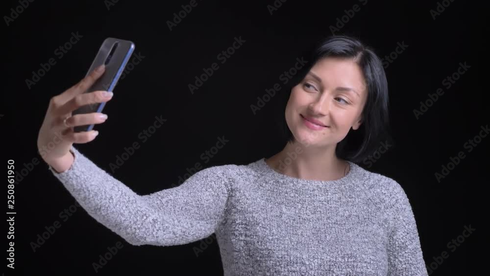 Closeup portrait of young beautiful caucasian female making selfies on the phone smiling and posing in front of the camera Closeup portrait of young beautiful caucasian female making selfies on the phone smiling and posing in front of the camera
