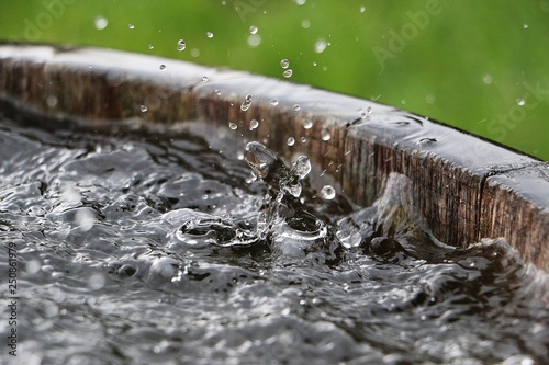 Quadro su tela rain is falling in a wooden barrel full of water in the garden