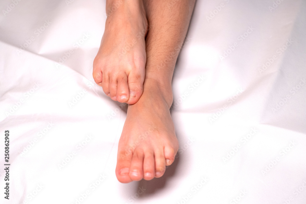 Woman foot flexion on bed sheets color white Woman foot flexion on bed sheets color white