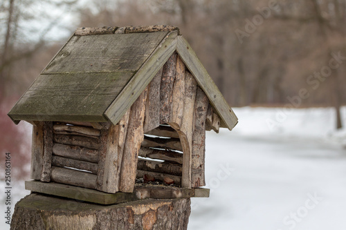 rustic style homemade bird feeder in the form of a hut for birds in winter © akintevs