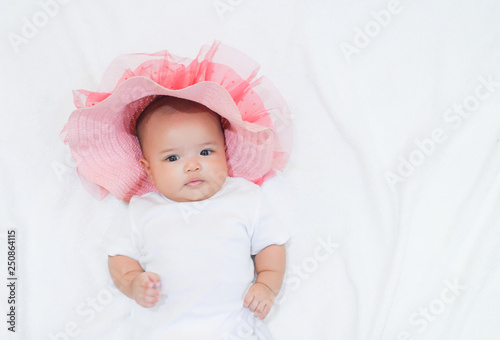 Asian newborn baby girl wear pink beach hat and white dress on white background. Baby and her beach wears on white towel background.