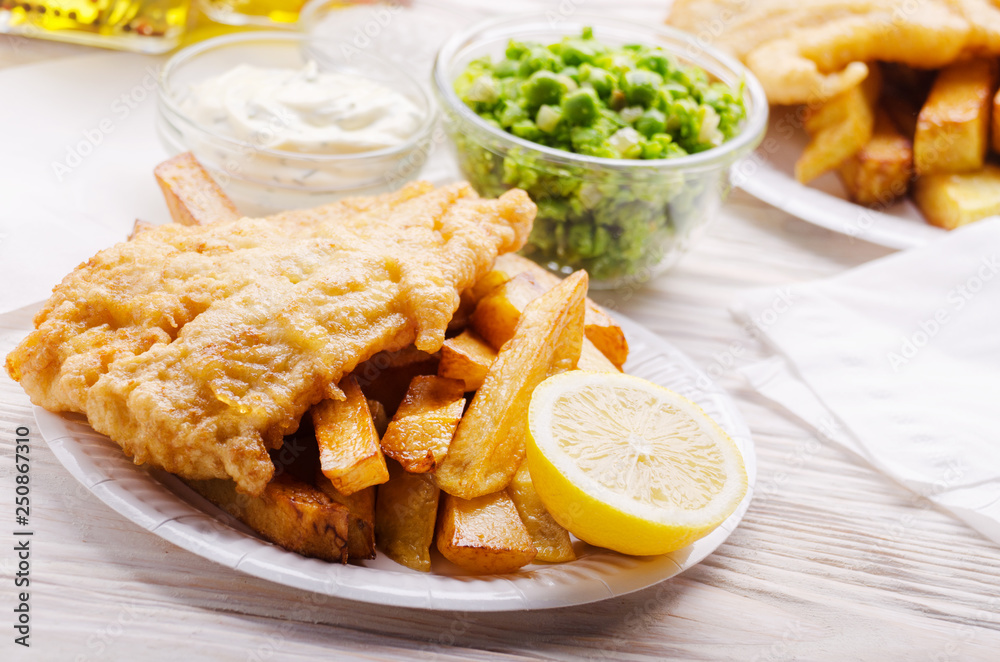 Traditional British street food fish and chips with tartar sauce and mushy peas on paper plate
