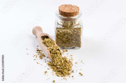 oregano herb in wooden scoop and jar on isolated on white background