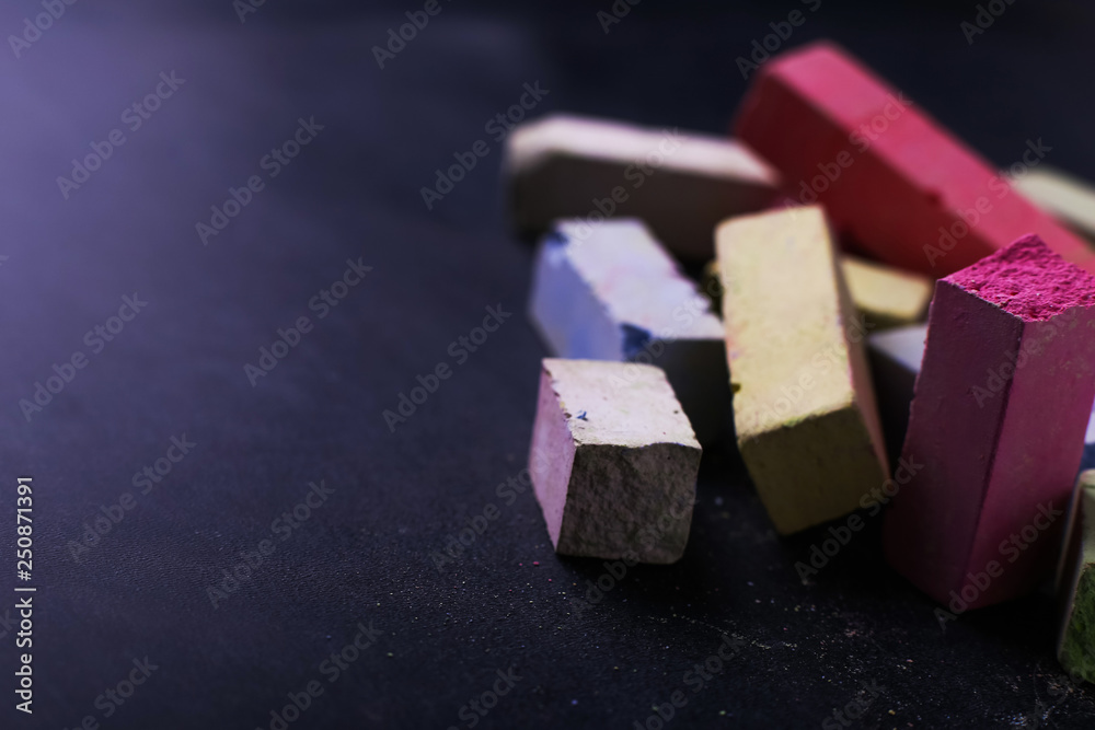 Multicolored crayons lie on a black chalkboard, copy space, macro. The concept of school, education and childhood. Multicolored crayons lie on a black chalkboard, copy space, macro. The concept of school, education and childhood.