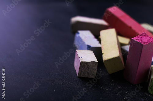 Multicolored crayons lie on a black chalkboard, copy space, macro. The concept of school, education and childhood. photo