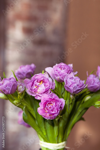 Bunch of pink spring flowers with green leaves at home, light beautiful purple tulips bouquet as nice romantic present from floral shop made by professional florist, vertical close up view copy space