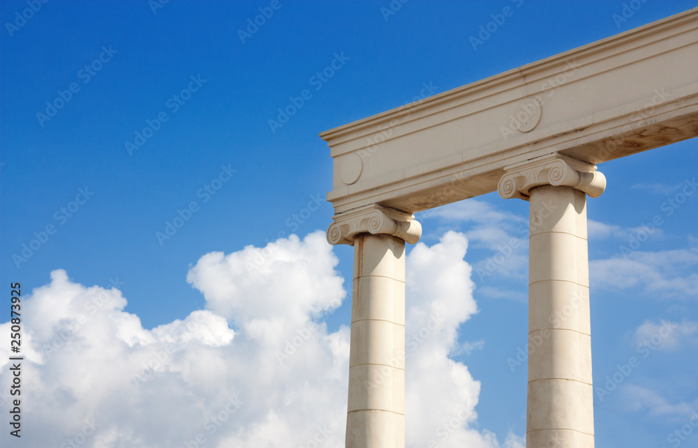 Antique columns against the blue sky and picturesque clouds