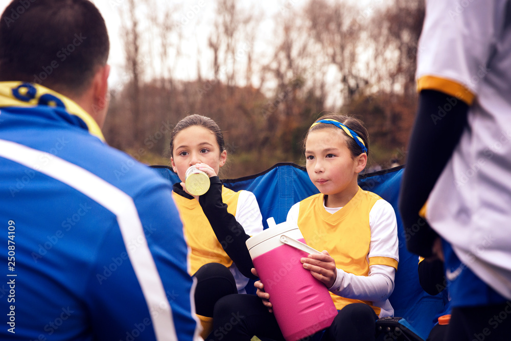 Girls during game break sitting with trainer in playground Girls during game break sitting with trainer in playground